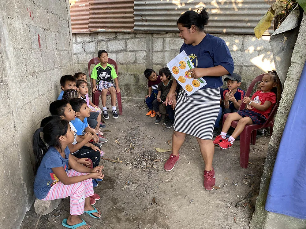 international-2 A woman teaches a small group of children outdoors.
