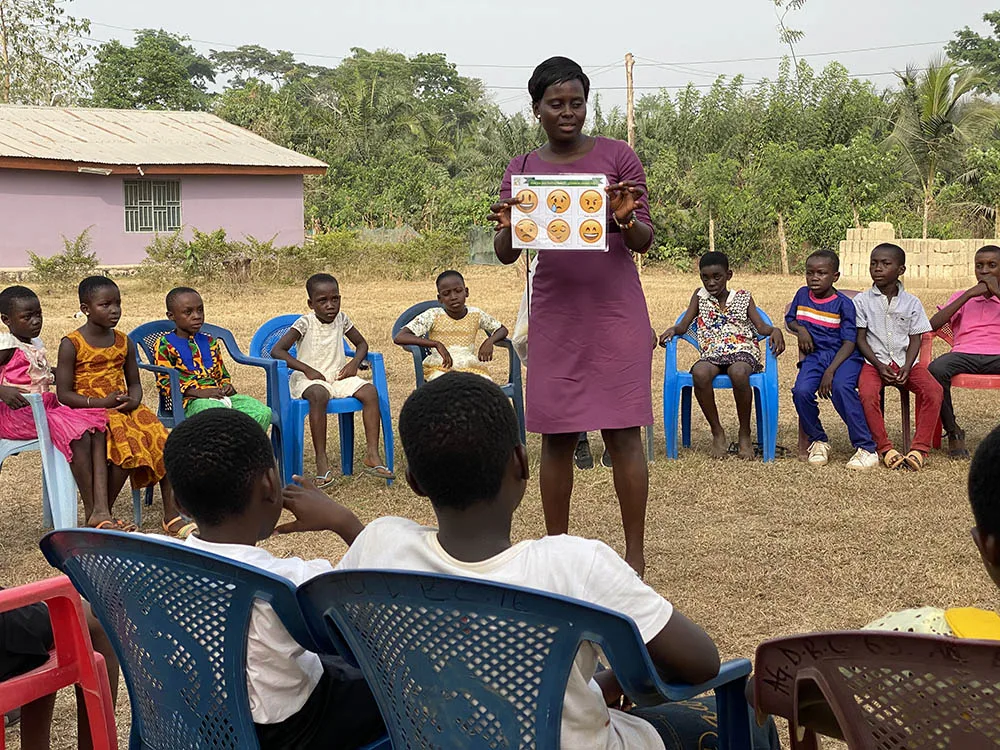 international-4 A woman teaches children during an outdoor Crossroads club.