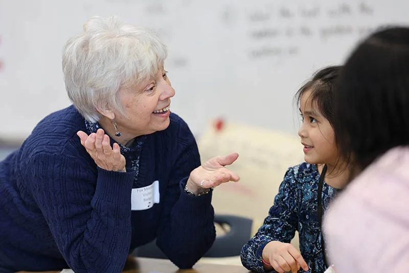 step-4-volunteer-training An adult volunteer talks with a child during a training activity.